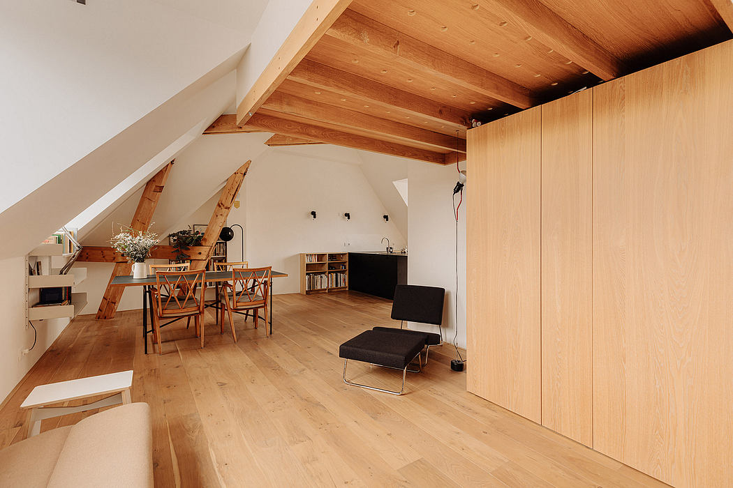 Spacious attic with wooden beamed ceiling, minimalist furnishings, and built-in storage.