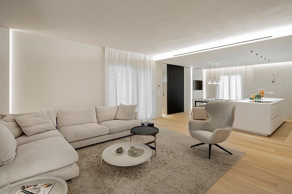 Spacious open-concept living area with minimalist furniture, neutral colors, and natural lighting.