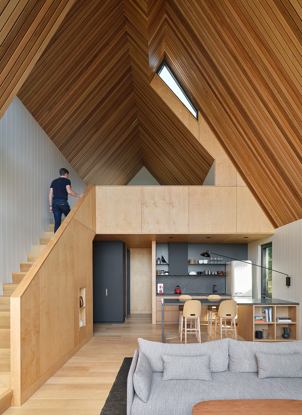 Striking wooden interior with angled ceiling and open kitchen layout.