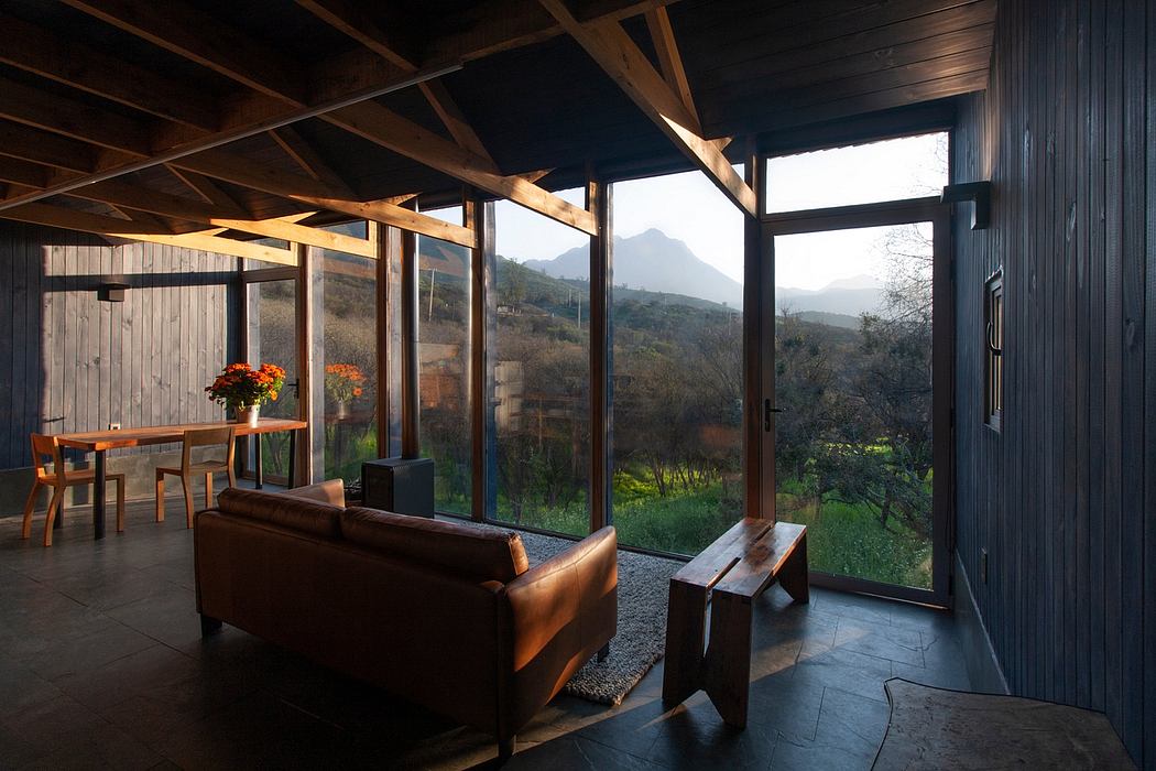 A rustic, wooden cabin interior with large windows offering a scenic mountain view.