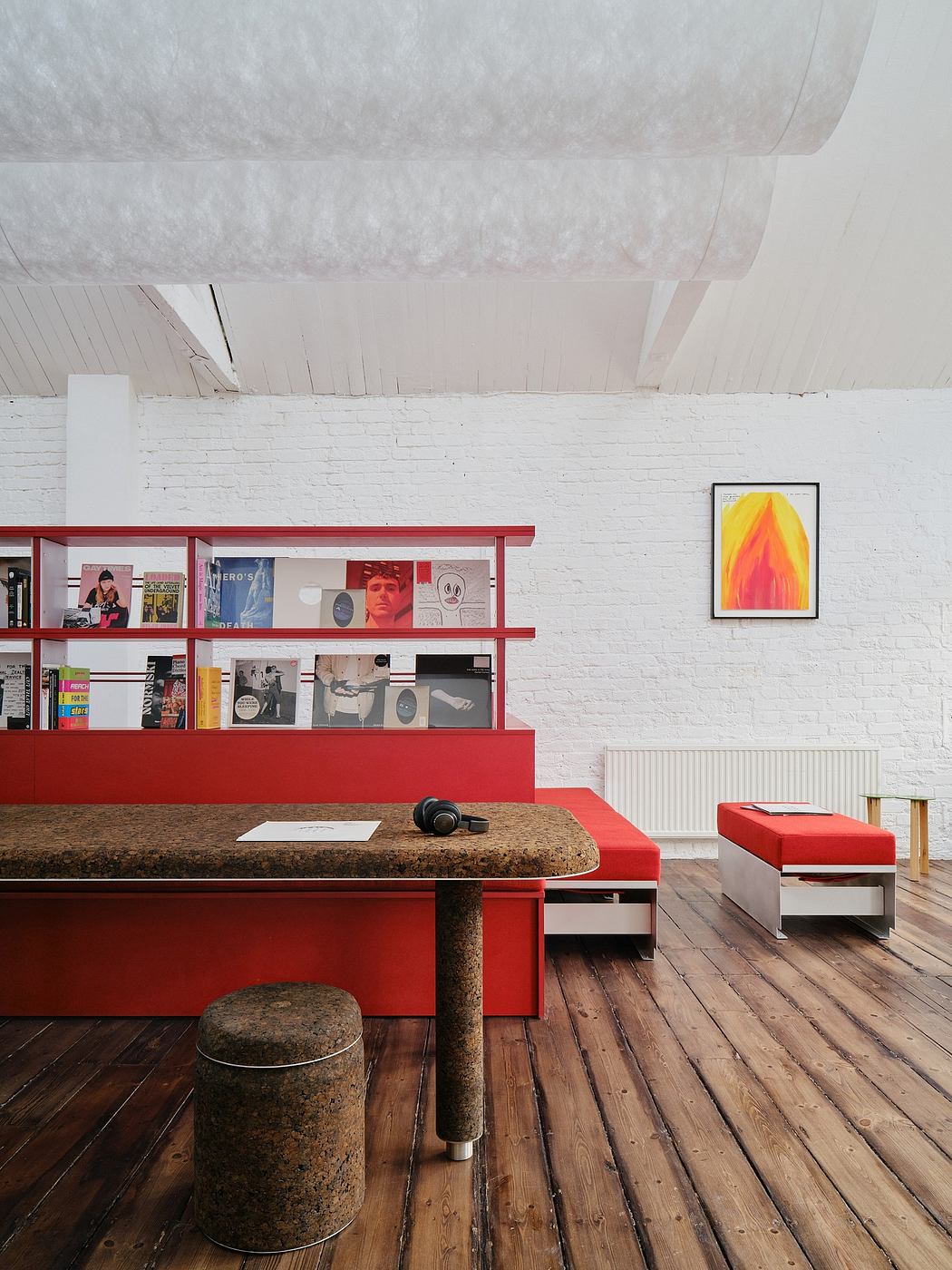 A modern study space with red shelving, a granite-topped desk, and a vibrant abstract painting.