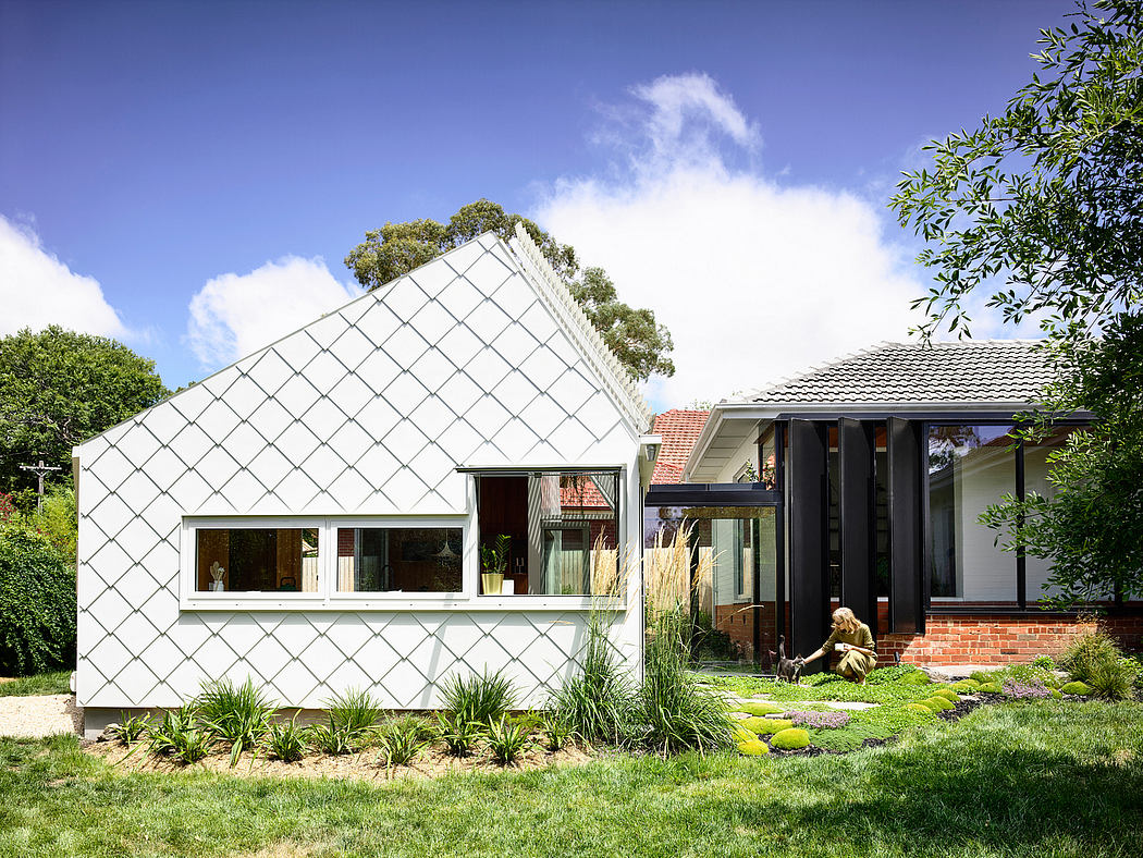 Modern, geometric exterior with large windows, brick accents, and lush landscaping.