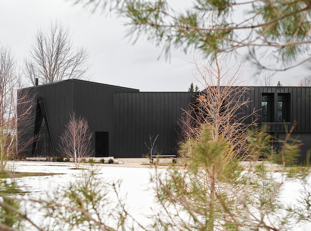 A striking, modern black building set against a snowy landscape, with clean lines and an angular design.