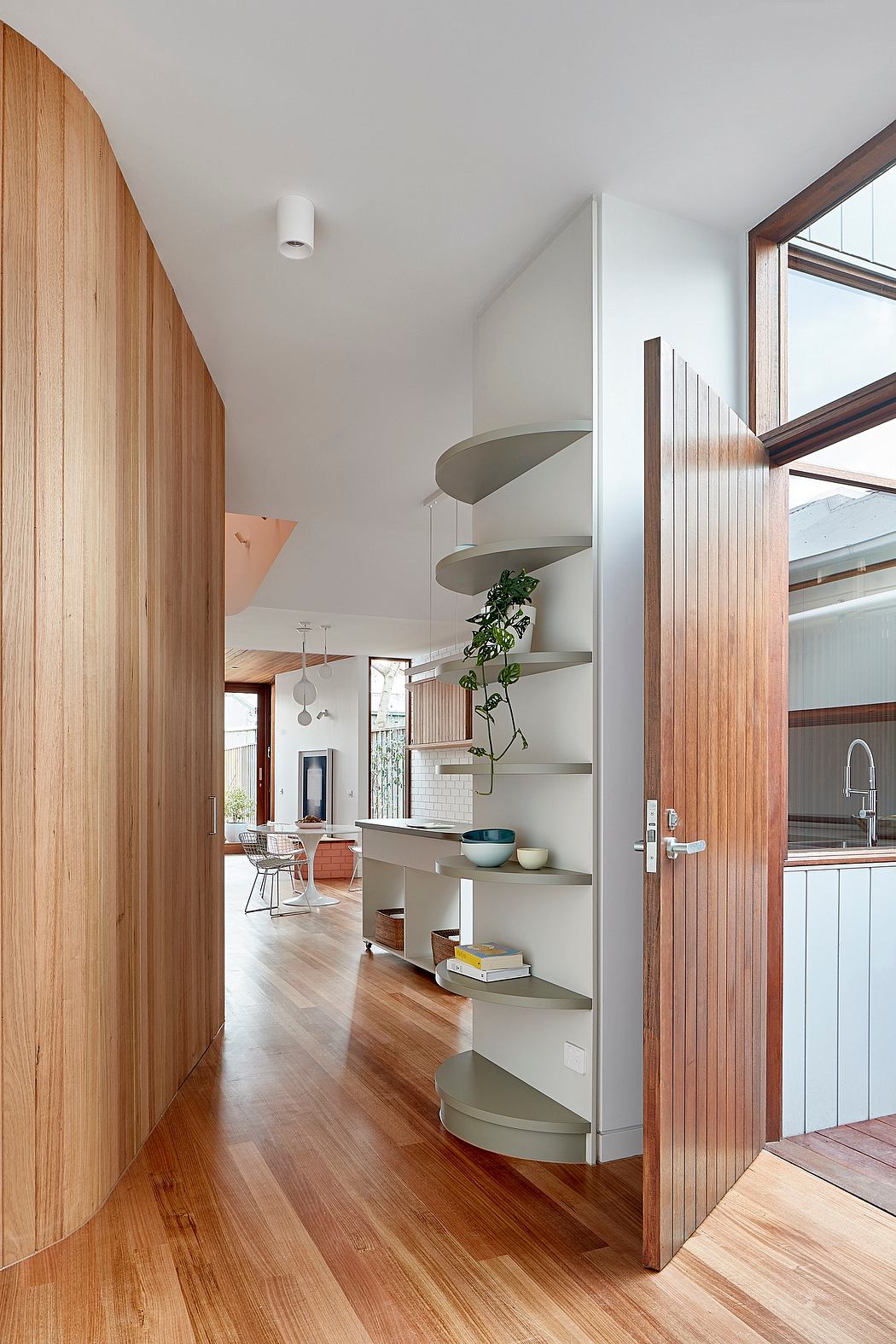 Spacious interior with wooden walls, curved shelving, and large windows providing natural light.