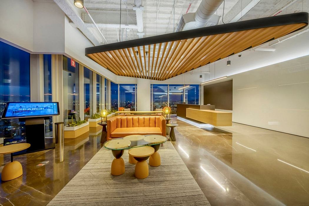 Spacious modern office lounge with wooden ceiling beams, plush seating, and glass walls.