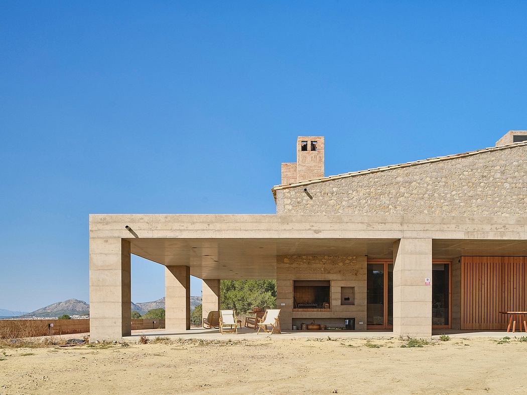 A rustic, stone-clad building with a covered patio, surrounded by a desert landscape.