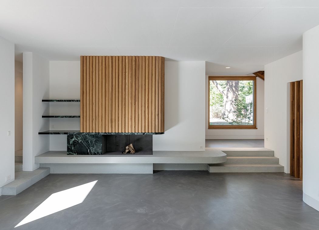 A modern living room with a wood-paneled fireplace, concrete floors, and a large window.