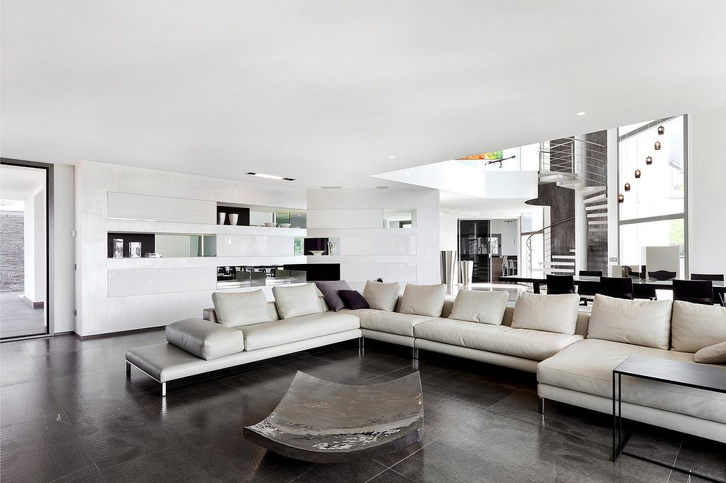 Spacious open-concept living space with minimalist white and grey decor, sleek sofas, and modern glass coffee table.