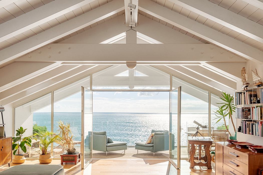 Spacious beachfront living space with vaulted ceilings, panoramic ocean views, and cozy seating.