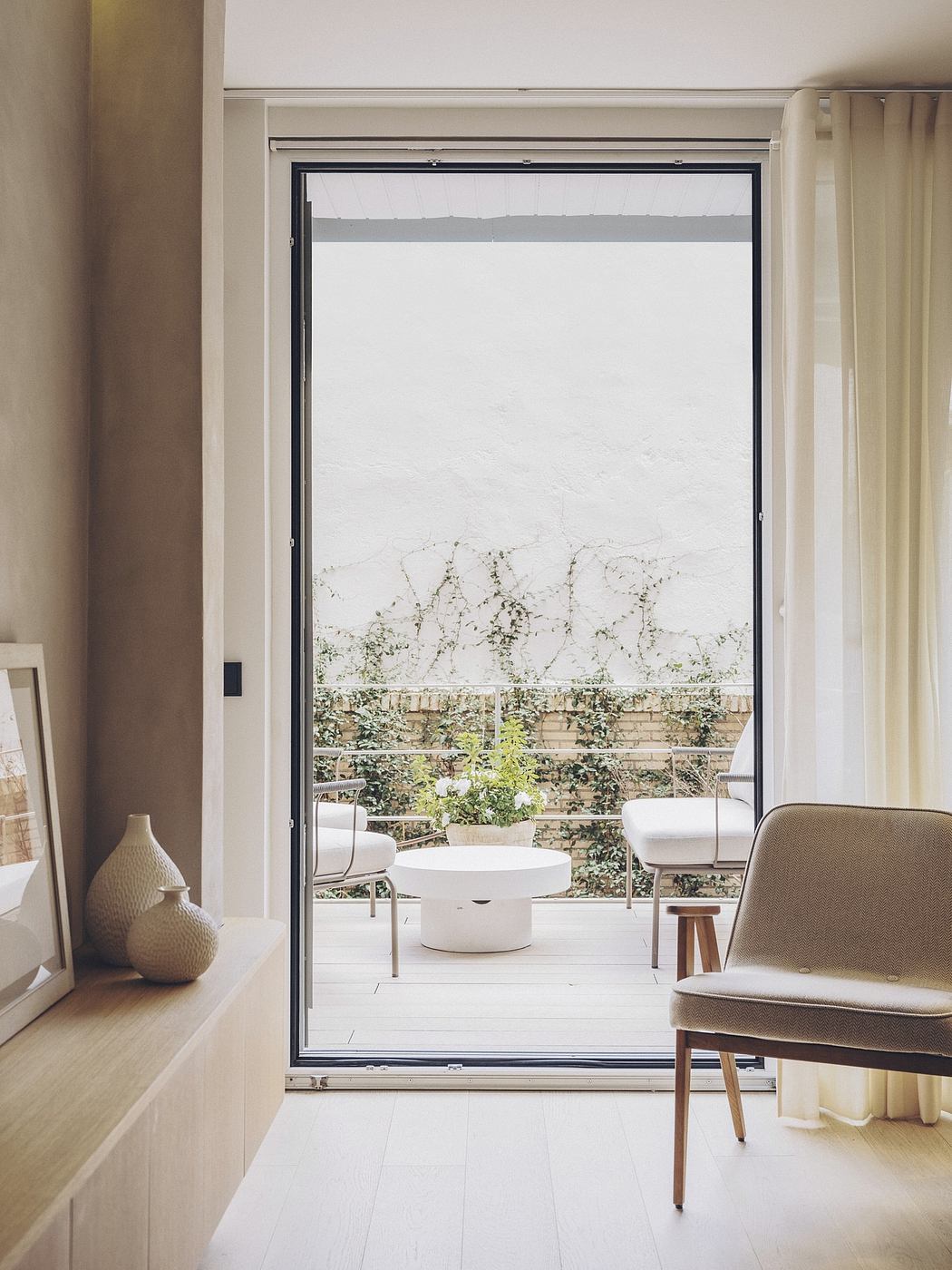 A clean, modern living space with large glass doors opening to a brick patio and garden.