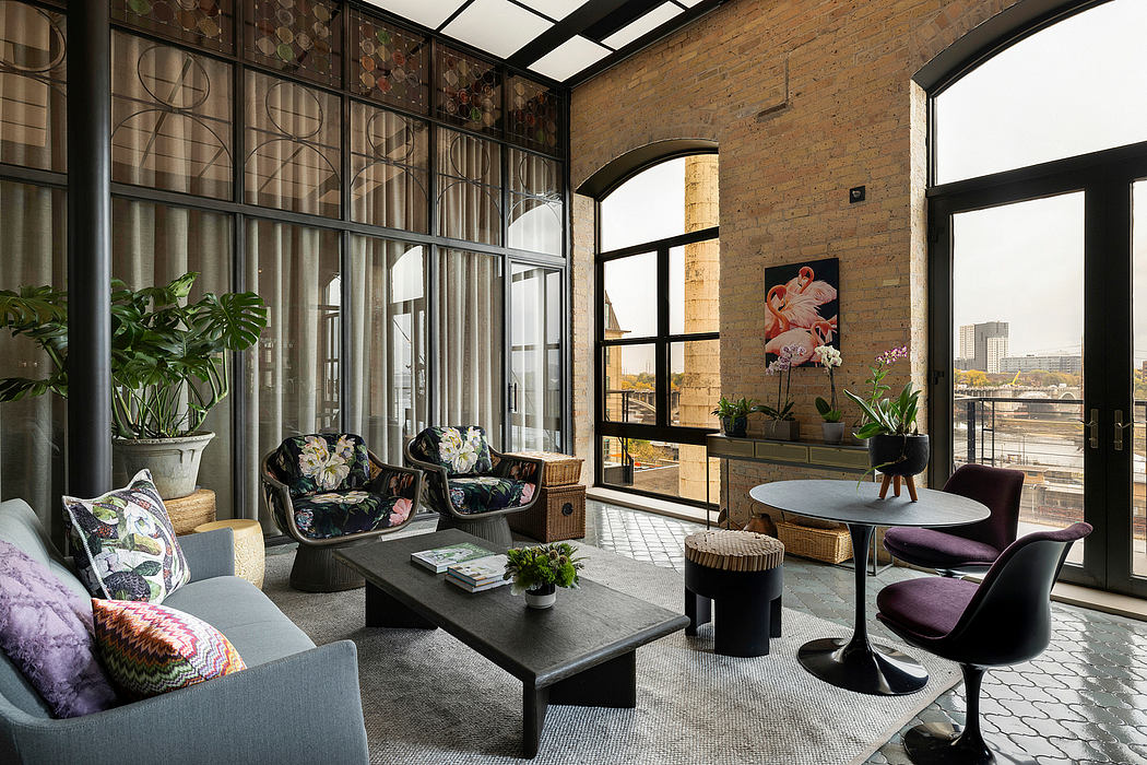 Spacious loft-style interior with industrial-chic decor, large windows, and modern furniture.