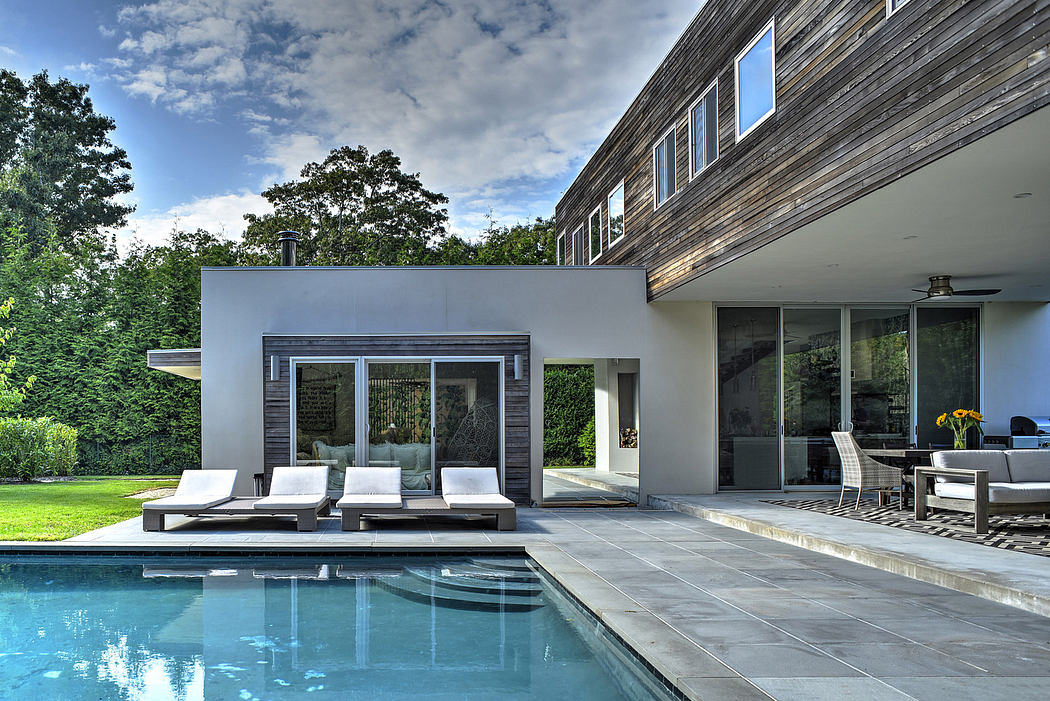 Modern, minimalist home exterior with a pool, deck, and lush landscaping. Sleek architectural design.
