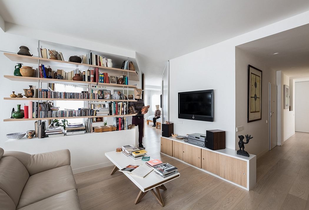 Spacious living room with extensive wall-mounted bookshelves, wooden TV stand, and minimalist decor.