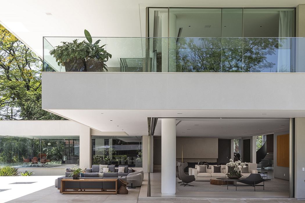 Minimalist modern home with large glass windows, open floor plan, and lush greenery.