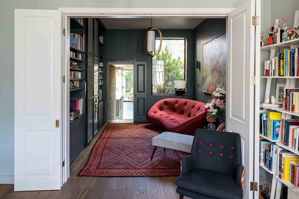 Eclectic living room with dark green walls, an ornate red sofa, and a patterned rug.