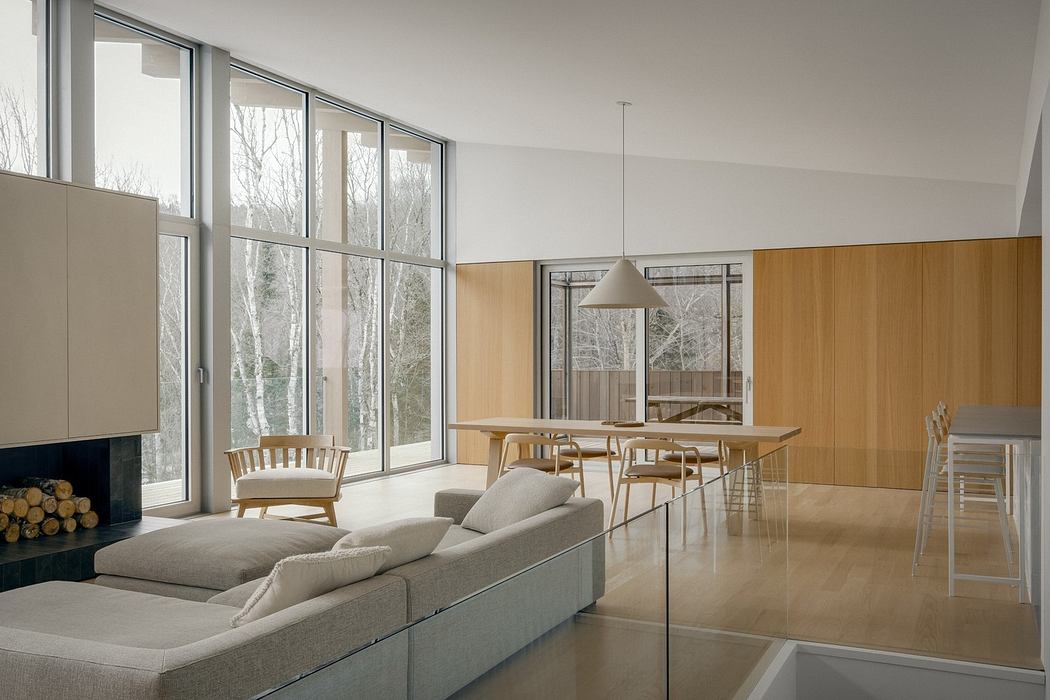 A modern, open-concept living space with large windows, wood paneling, and a fireplace.