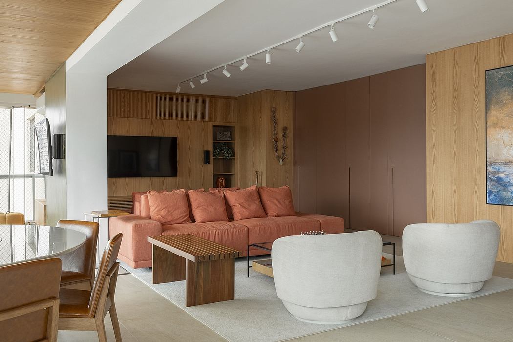Modern living room with wood paneling, track lighting, and plush coral sofa.