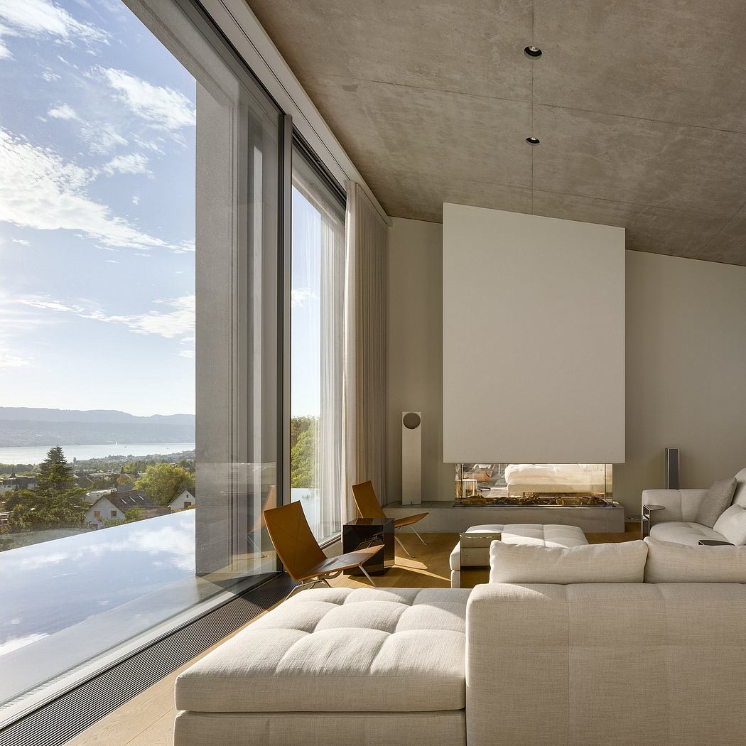 A modern living space with large windows overlooking a scenic landscape, featuring a fireplace and comfortable seating arrangements.