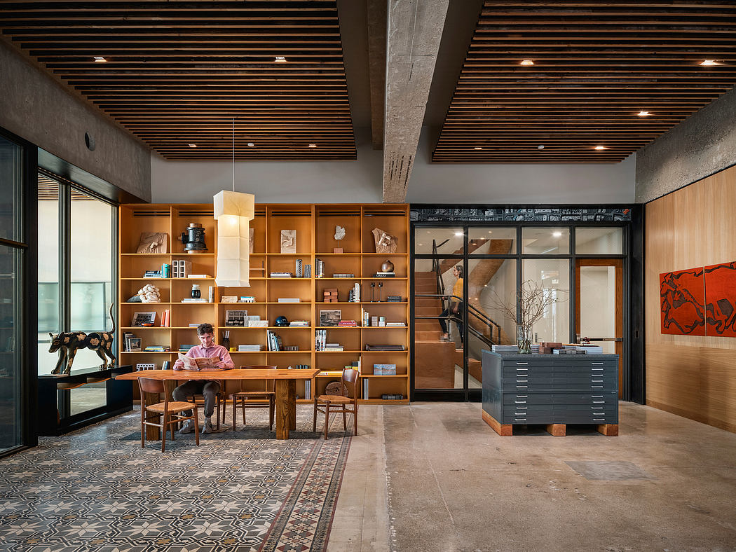 Expansive wooden shelving, concrete ceiling, and patterned tile floor create a warm, industrial space.