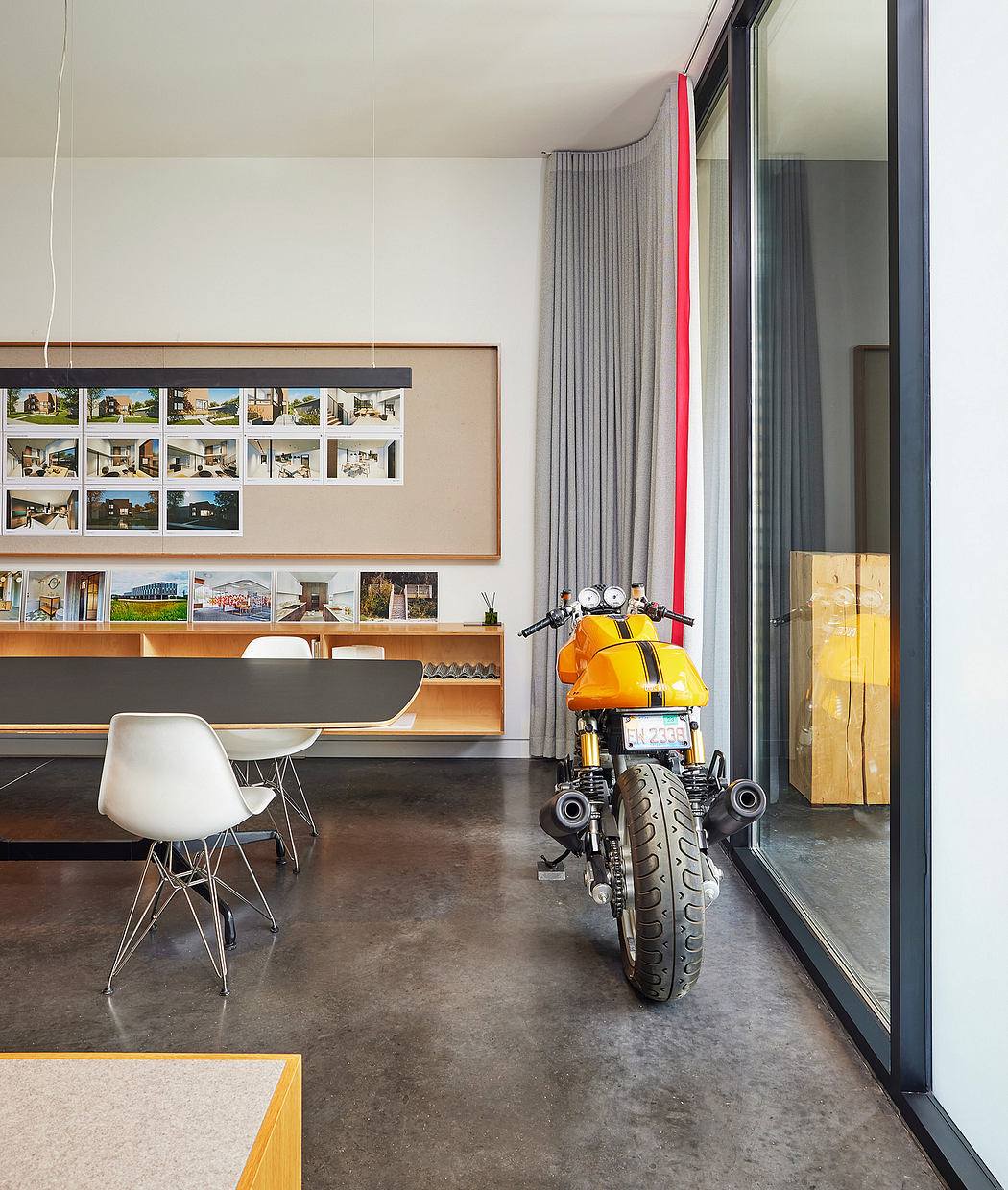 Modern, minimalist interior with concrete floor, large window, and yellow motorcycle.