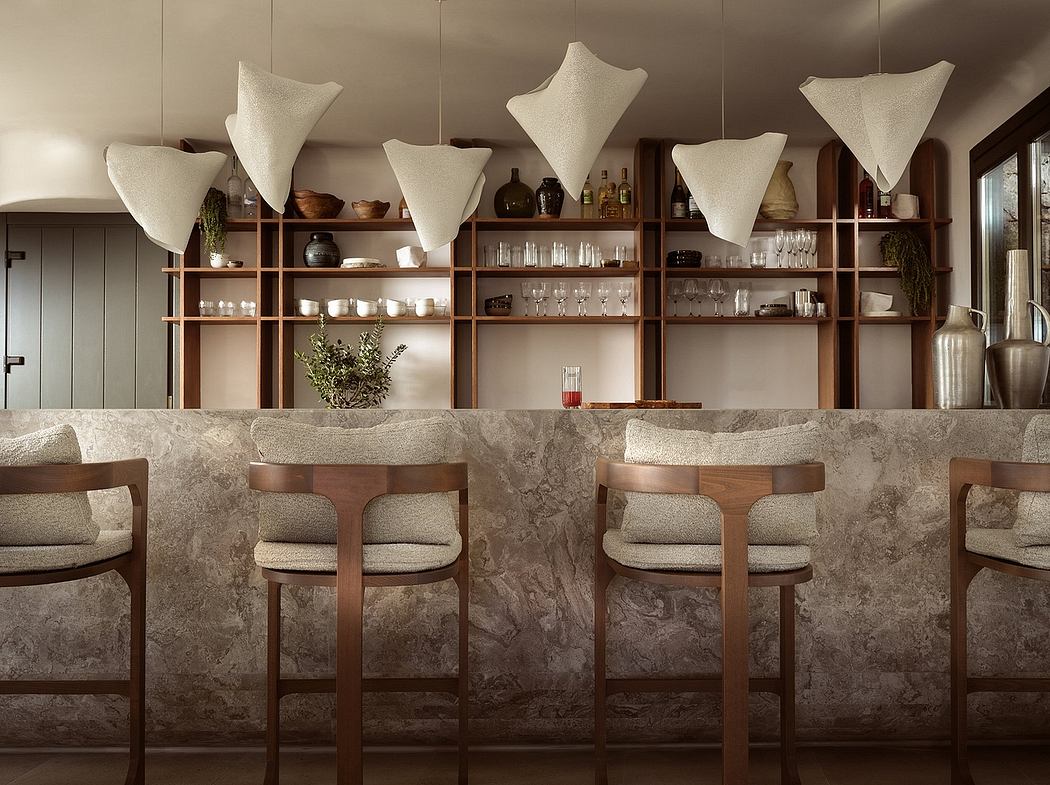 Elegant wood-and-stone bar with artistic lighting and shelving displaying glassware.