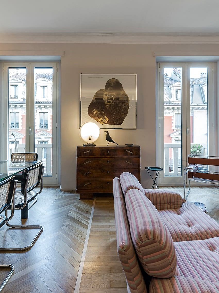 A cozy living room with large windows, a plush pink sofa, and a striking abstract artwork.