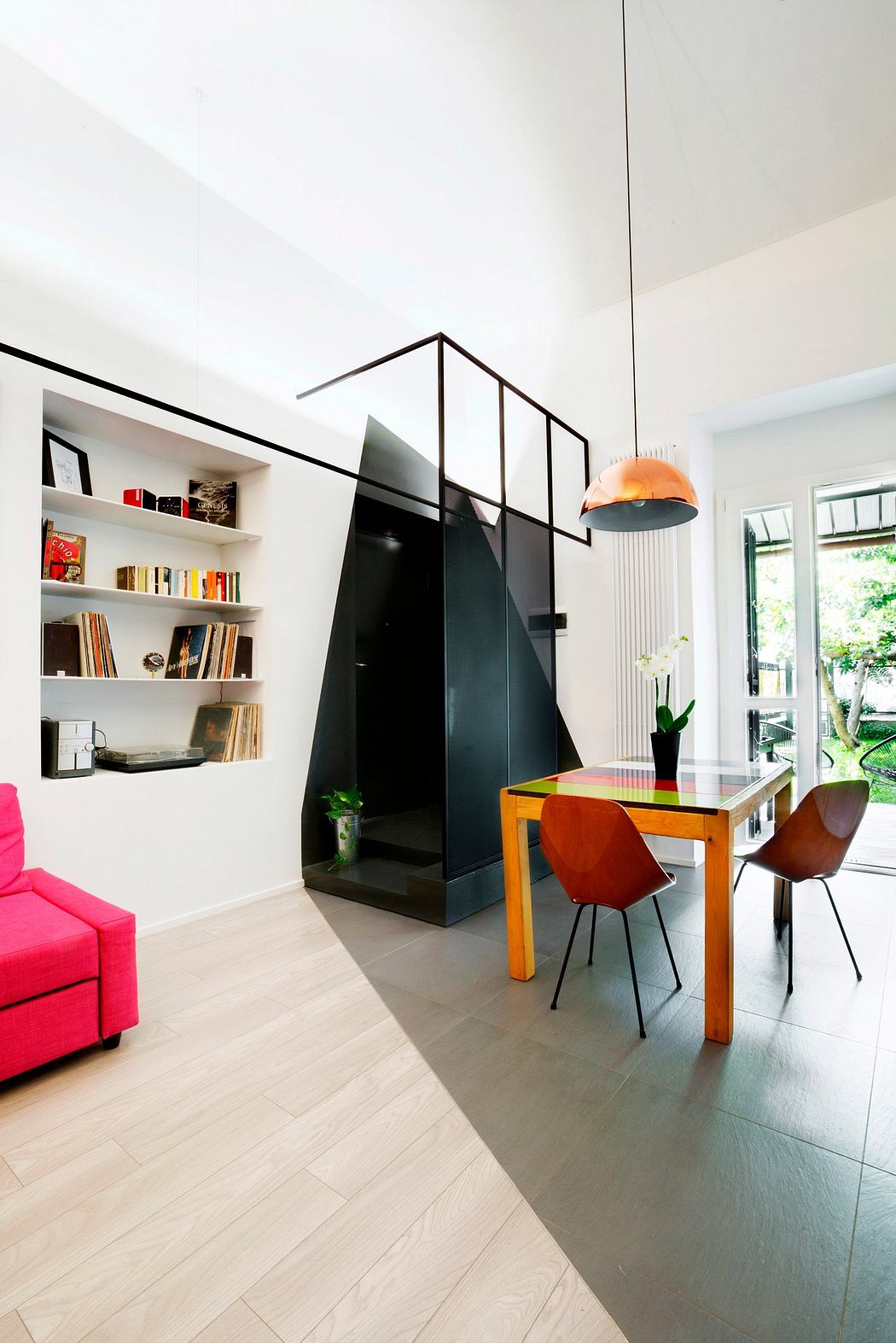 Modern, open-plan living space with sleek black architectural features, vibrant furnishings, and ample natural light.