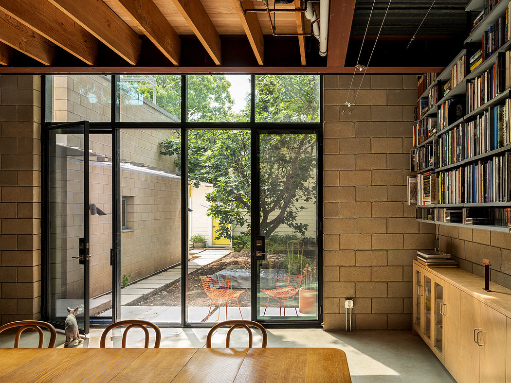 Spacious modern room with exposed wooden beams, large windows, and a cozy outdoor seating area.