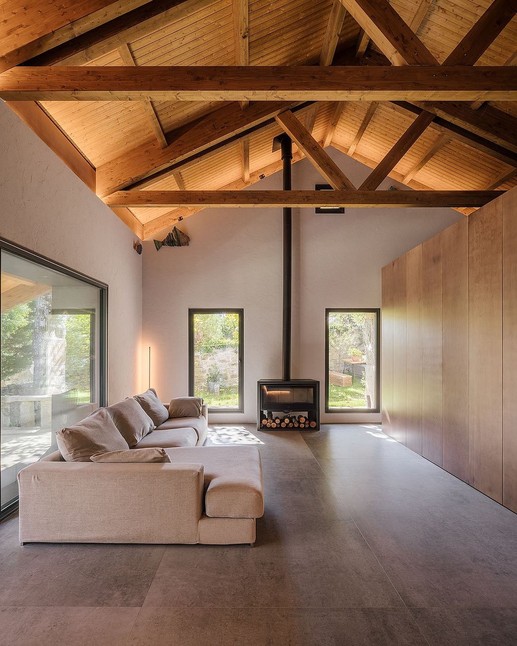 Cozy living room with exposed wooden beams, concrete floor, and a wood-burning stove.