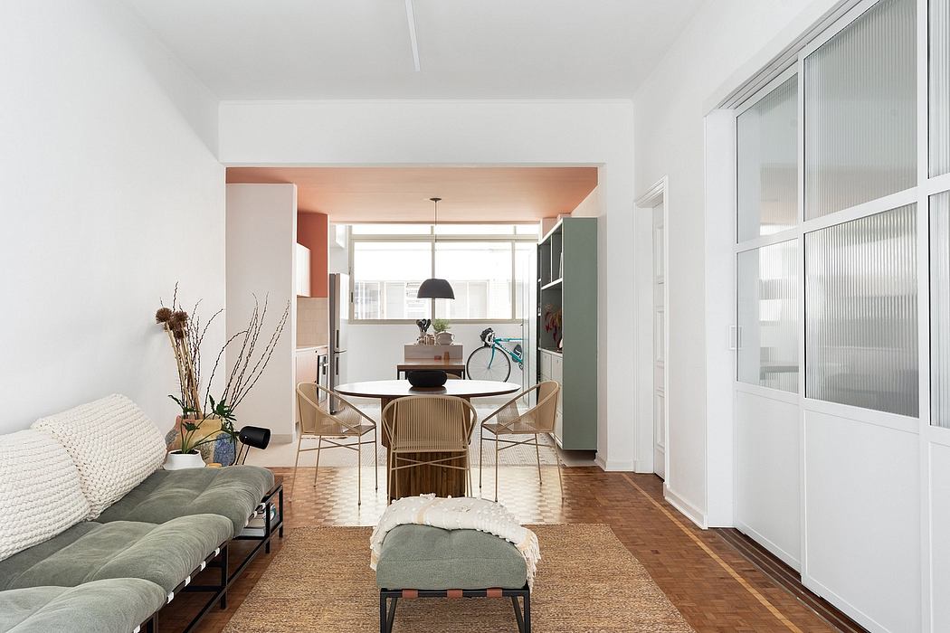 A modern open-plan living space featuring a round dining table, wood-paneled walls, and minimalist decor.