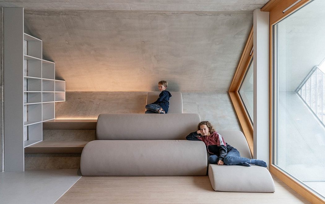 Minimalist, open-concept interior with concrete walls, built-in shelves, and cozy seating.
