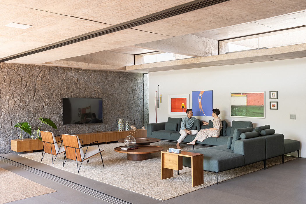 A modern living room with exposed concrete walls, sleek wooden furniture, and vibrant artworks.