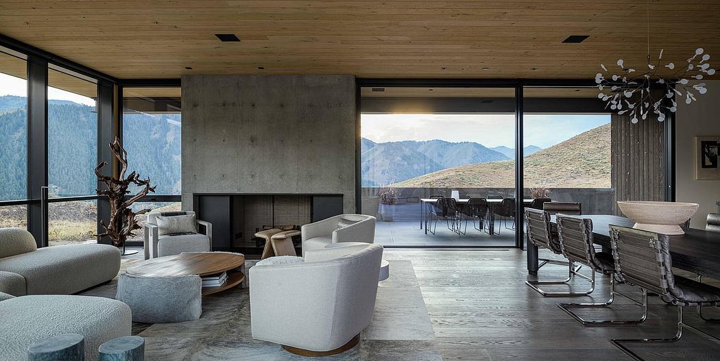 A spacious modern living room with concrete walls, wooden ceilings, and a scenic mountain view.