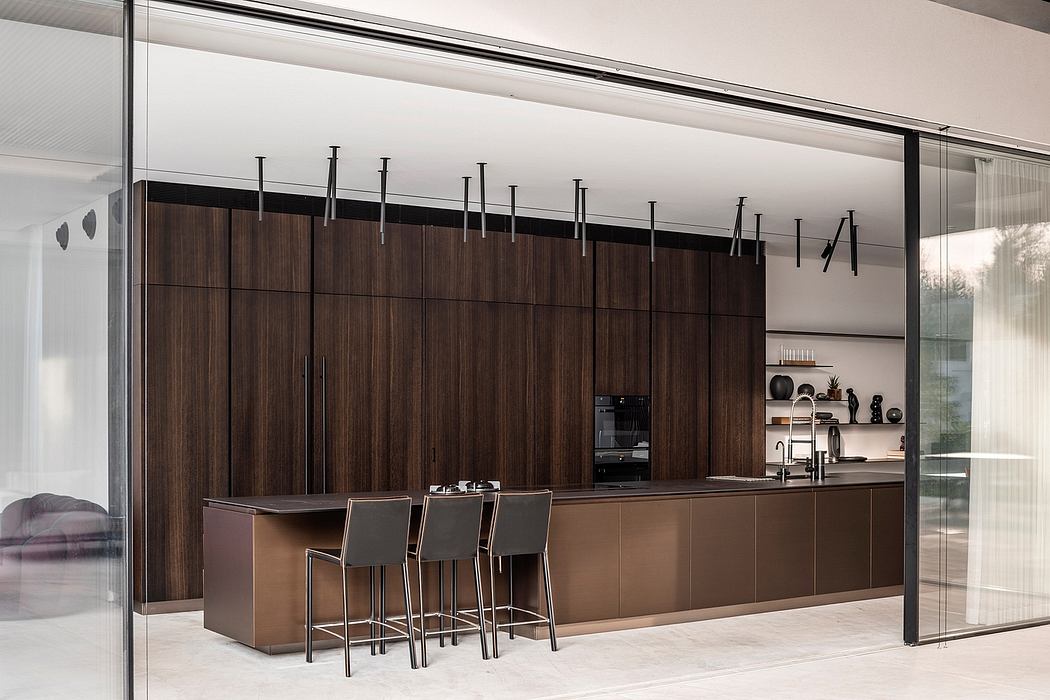 Sleek, modern kitchen design with dark wood panels, metal fixtures, and bar seating.