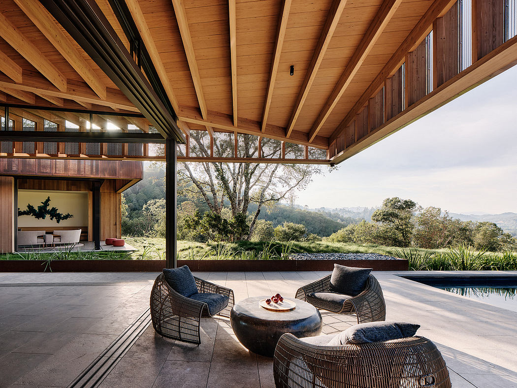 A modern, open-concept home with an expansive outdoor patio, pool, and panoramic forest views.