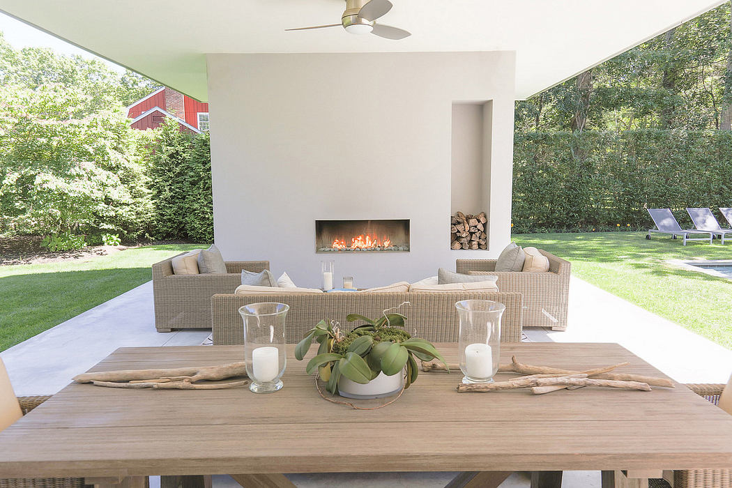 Cozy outdoor living space with wicker furniture, fireplace, and lush greenery.