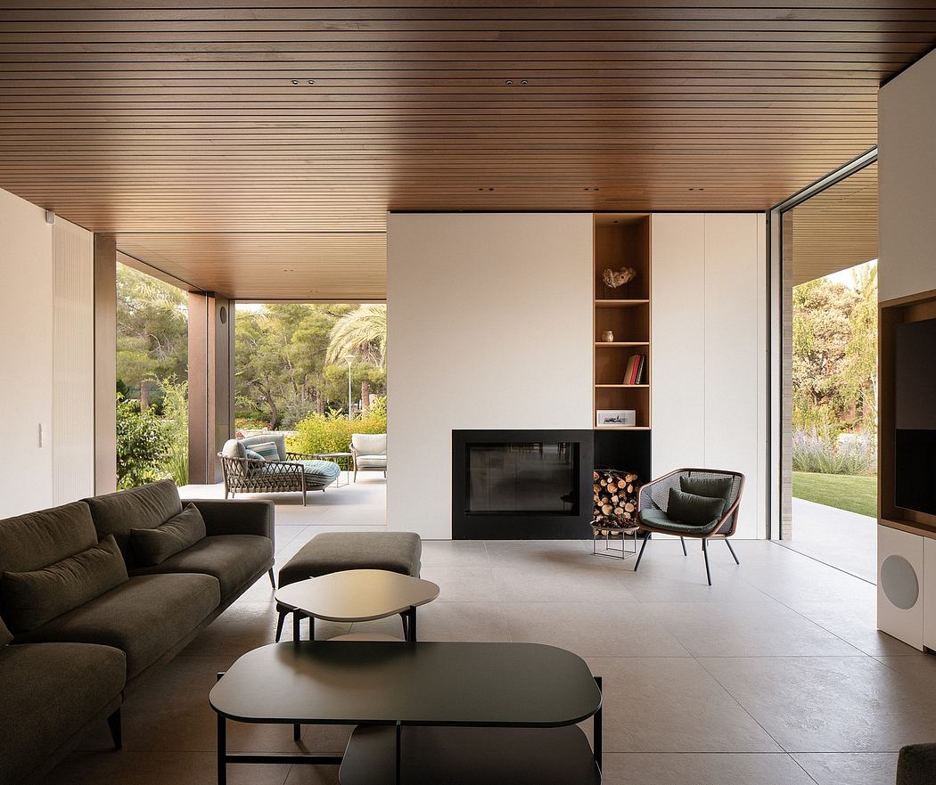 Sleek modern living space with wood-paneled ceiling, fireplace, and large windows overlooking nature.