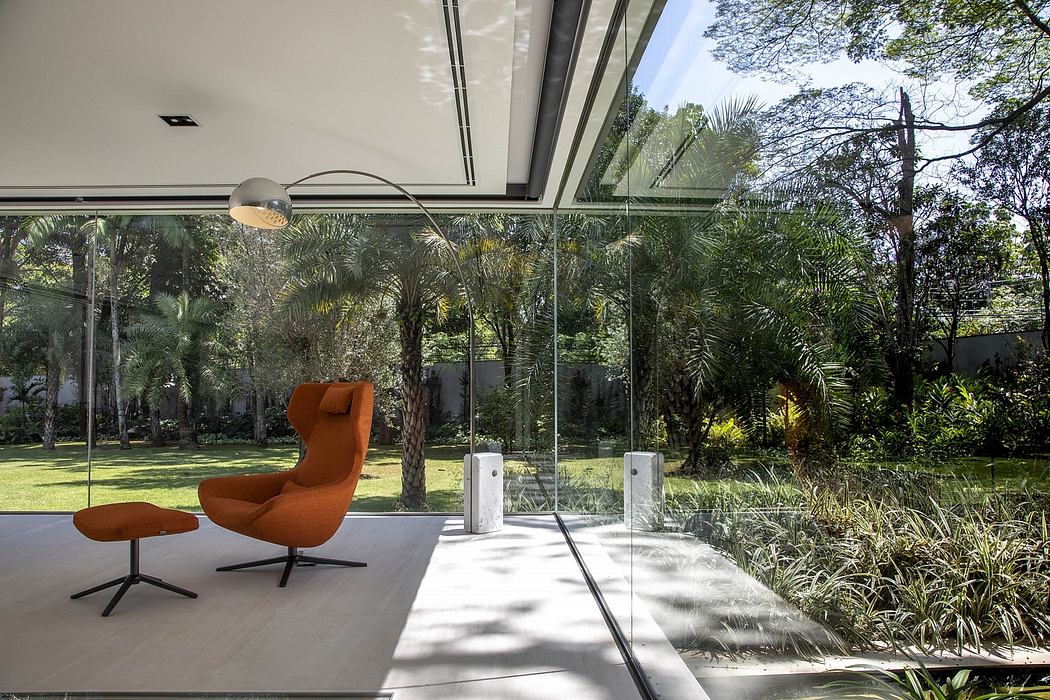 An elegant, glass-enclosed living space surrounded by a lush, tropical garden.