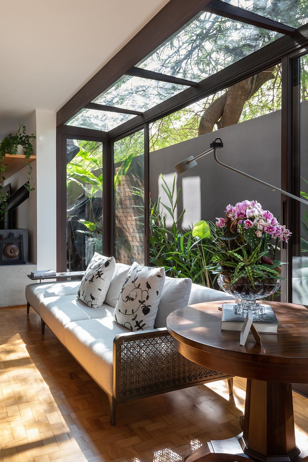 Cozy living area with large glass skylight, potted plants, and patterned pillows on a woven couch.