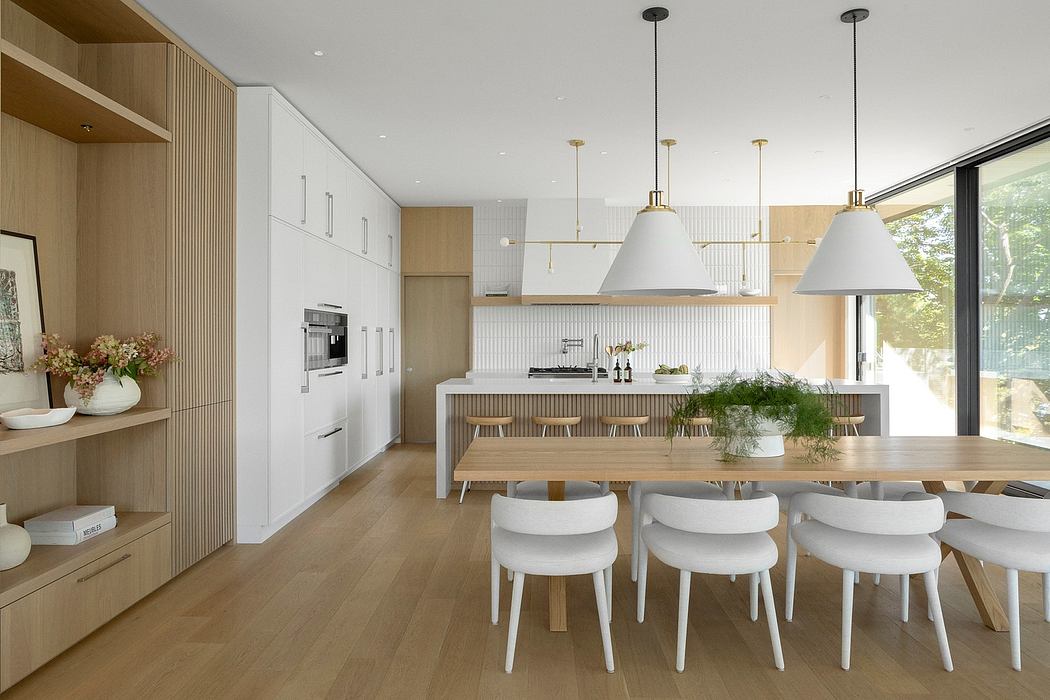 Sleek, modern kitchen and dining area with wood accents, white furniture, and pendant lights.