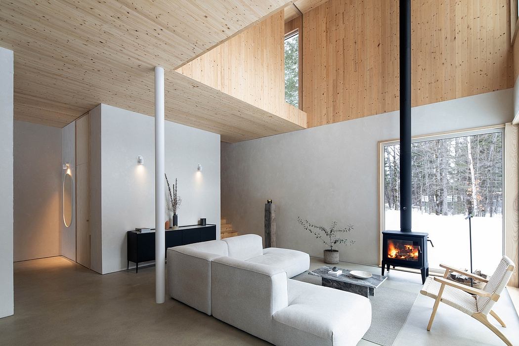 Cozy wooden cabin interior with high ceilings, fireplace, and minimalist decor.