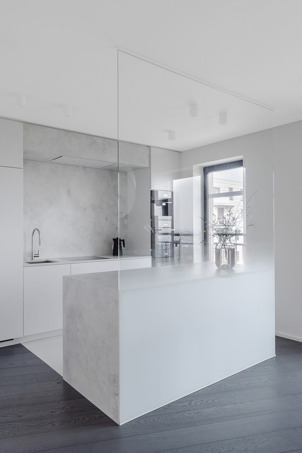 Minimal kitchen design with concrete surfaces, sleek built-in appliances, and large window.