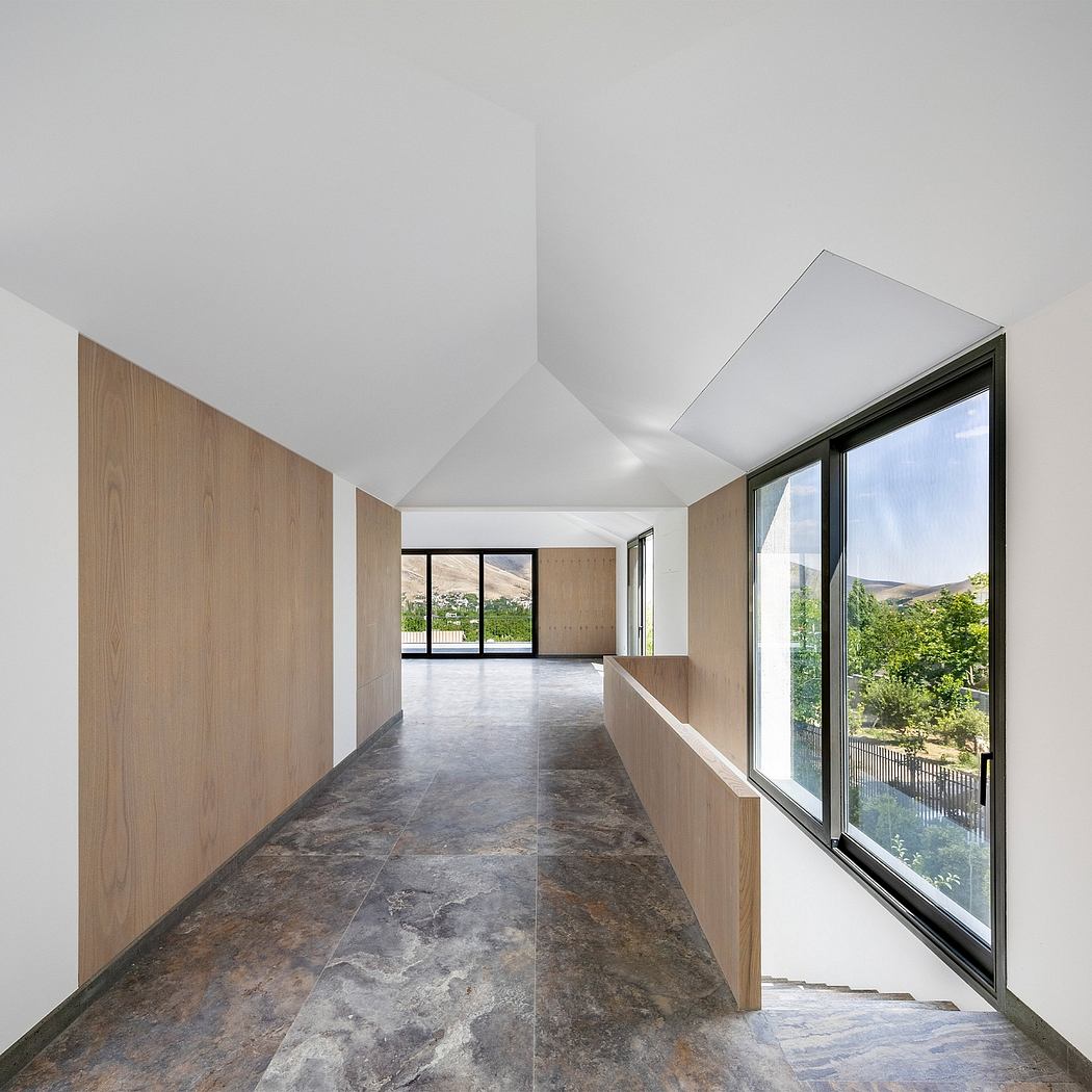 Spacious interior with wooden walls, stone floor, and large window overlooking greenery.