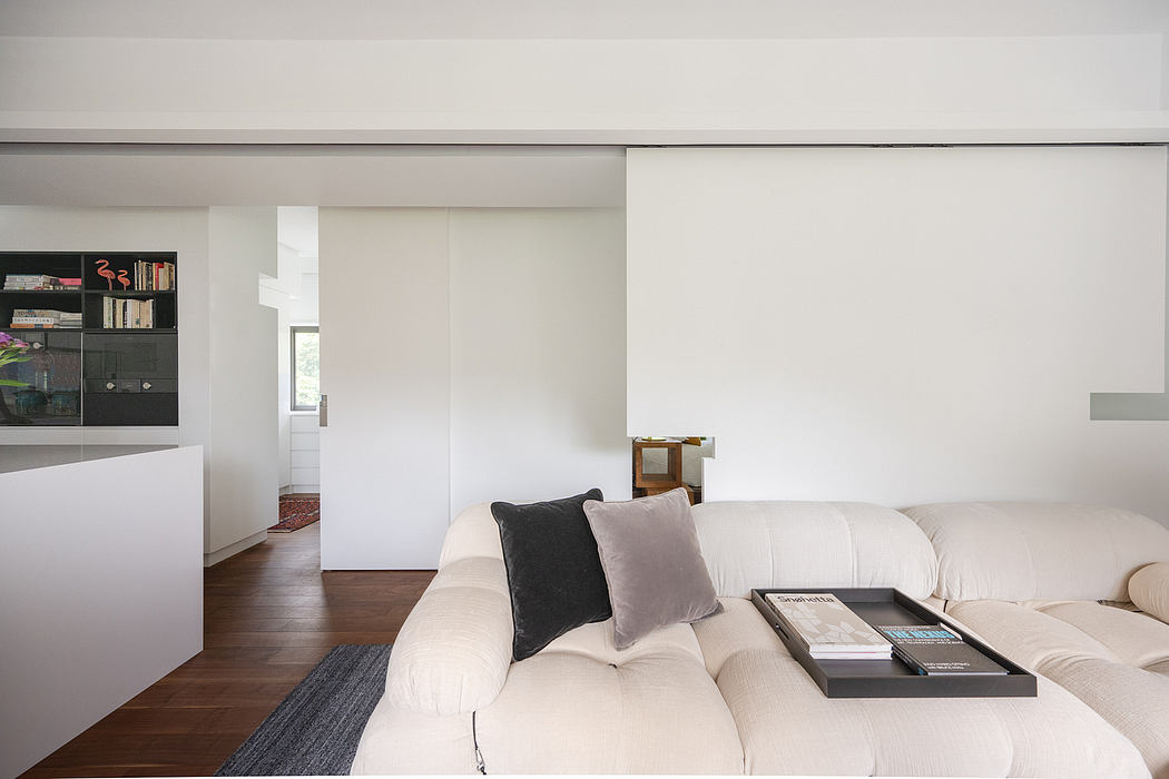 Minimalist living room with wooden floor, white walls, and built-in shelving.