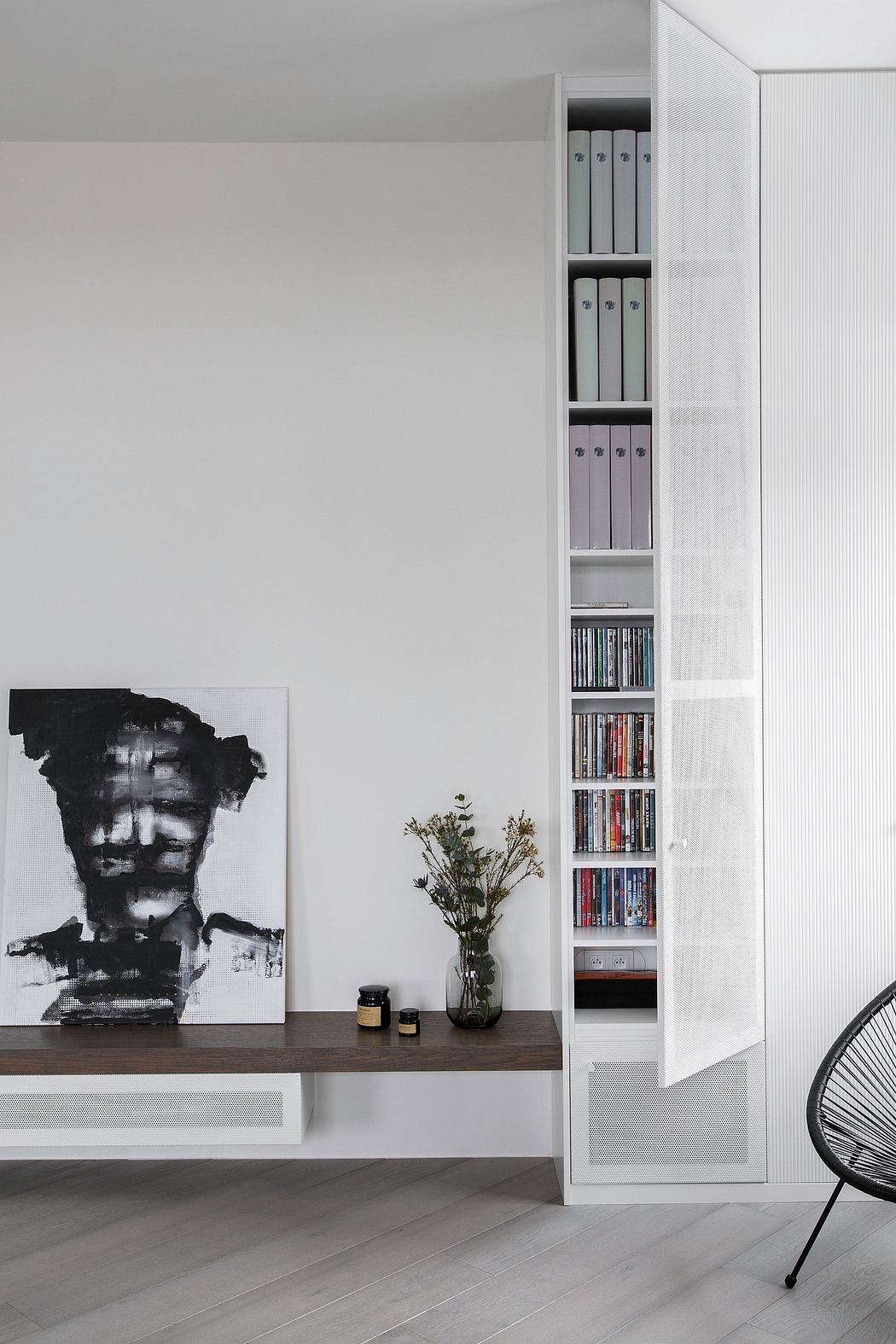 A minimalist living room with a large abstract painting, built-in shelving, and a potted plant.