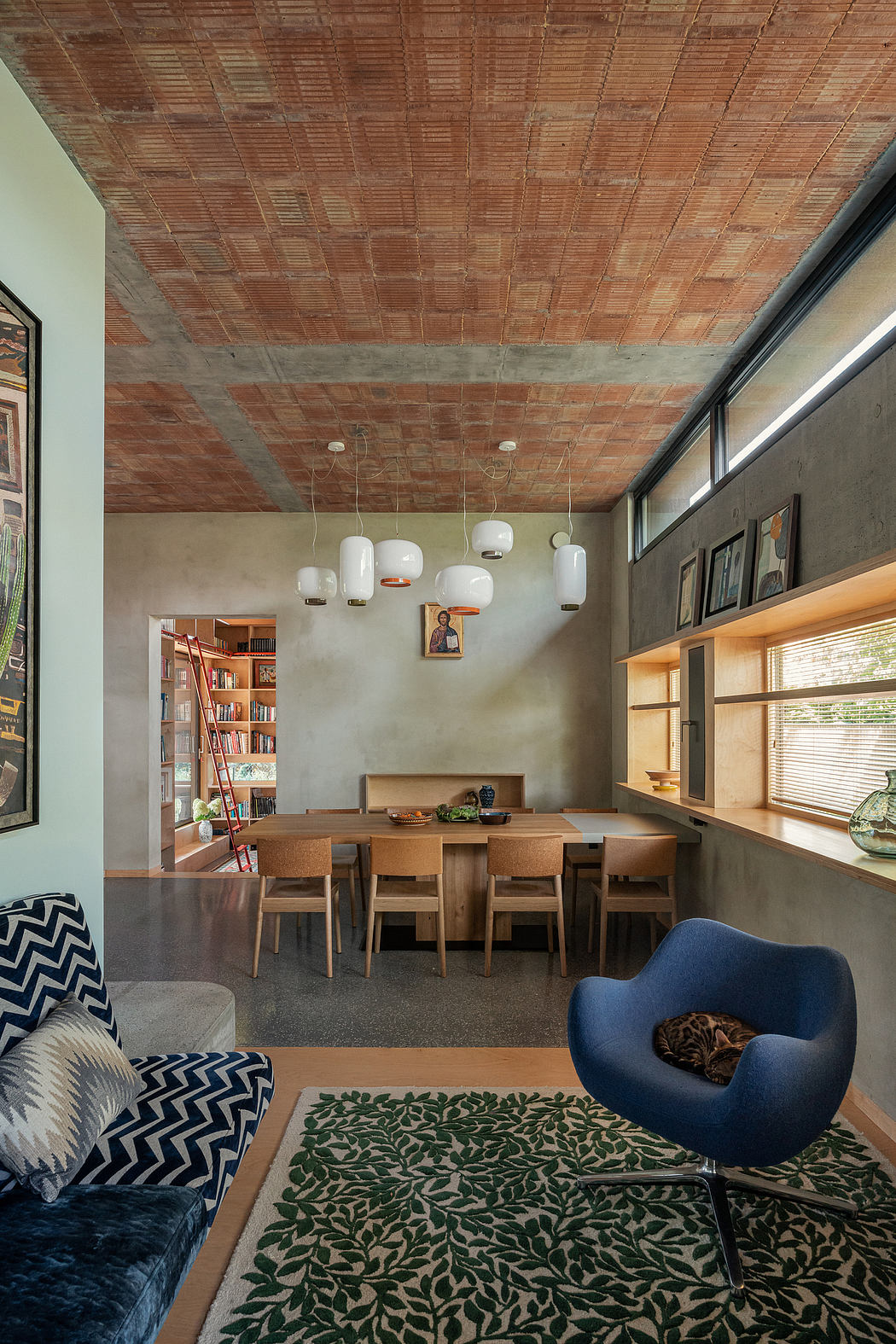A cozy dining area with exposed brick ceiling, pendant lighting, and a plush chair.