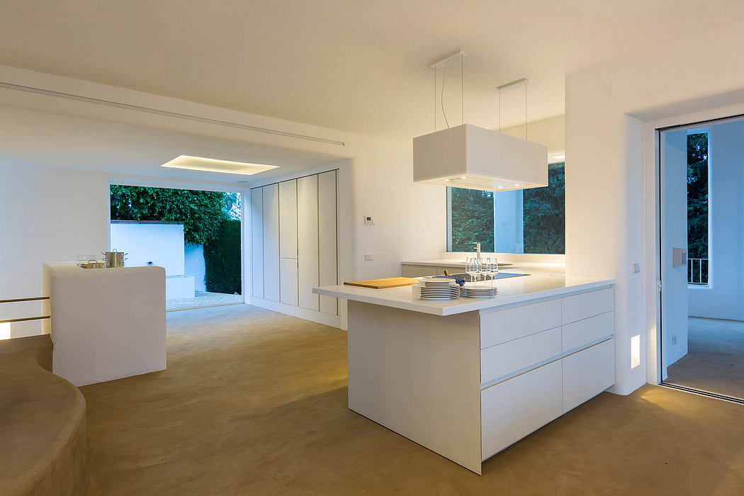 Minimalist kitchen design with sleek white cabinets, recessed lighting, and garden view.