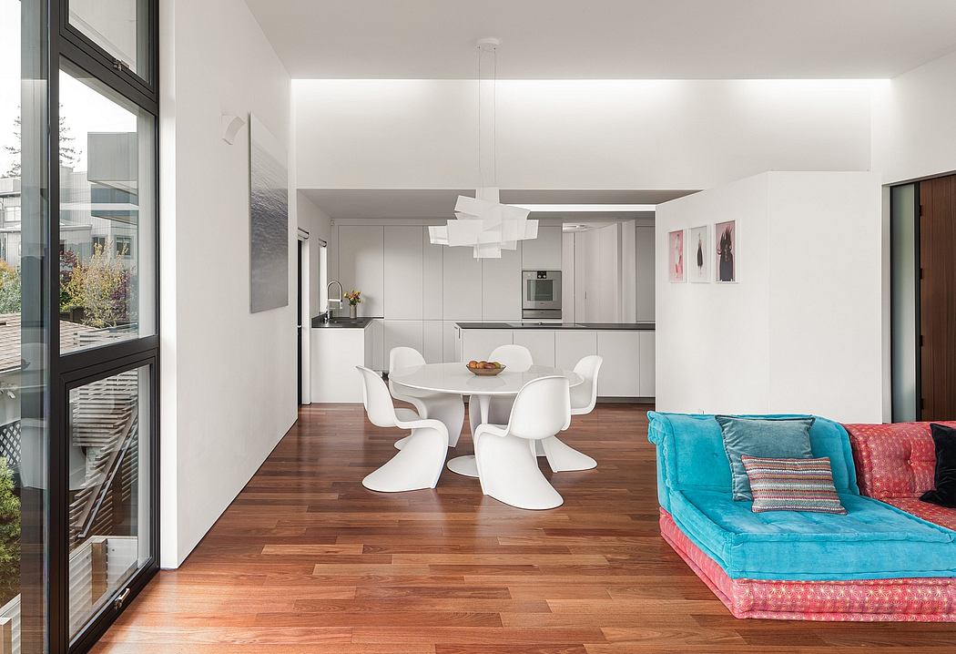 Bright, modern living space with white furniture, hardwood flooring, and colorful accents.