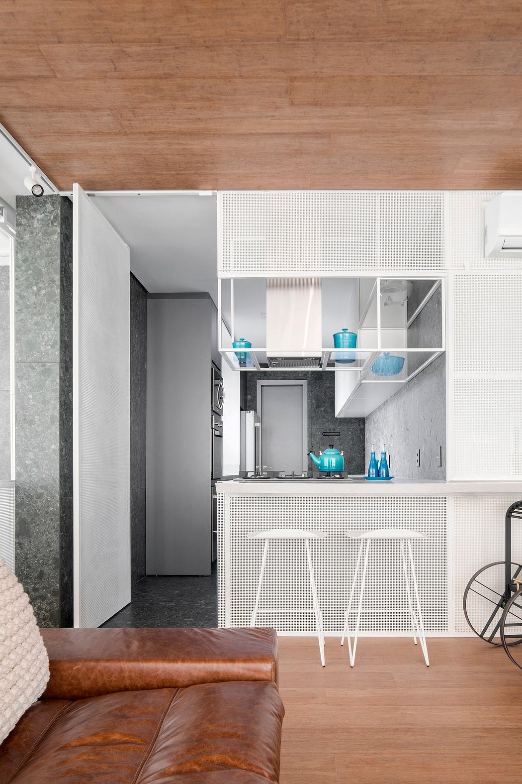 This modern studio apartment features a minimalist, open-plan layout with sleek kitchen cabinetry and bar stools.