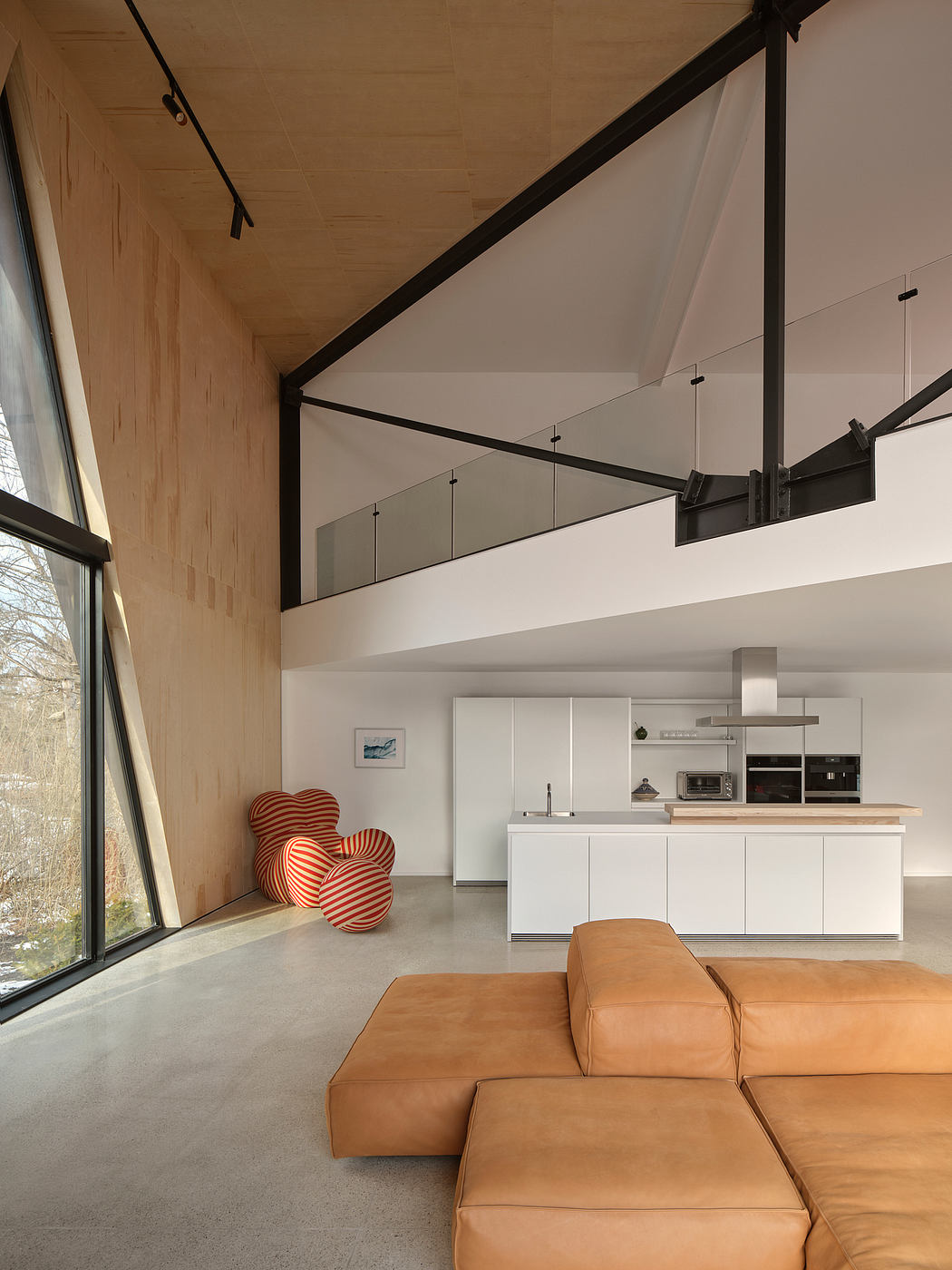 Modern loft interior with white cabinetry, wooden accents, and striking red cushions.
